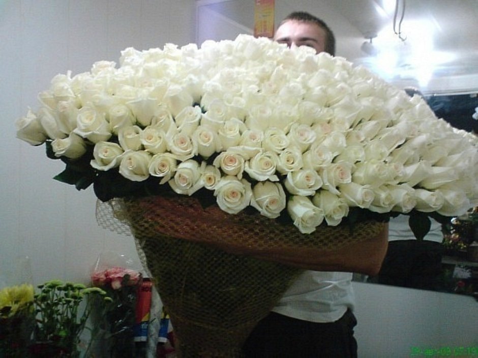 Парень с огромным букетом белых роз